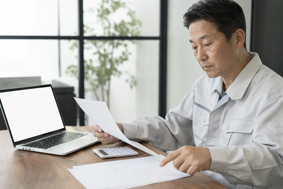 ccus イン ボイス対応を確認する建設事業者の手元と書類